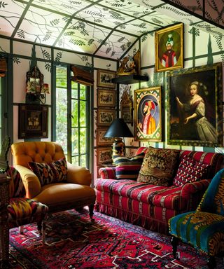 a maximalist living space with a sofa and chair and plants painted on the ceiling