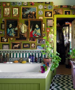 a maximalist bathroom with green walls and artwork